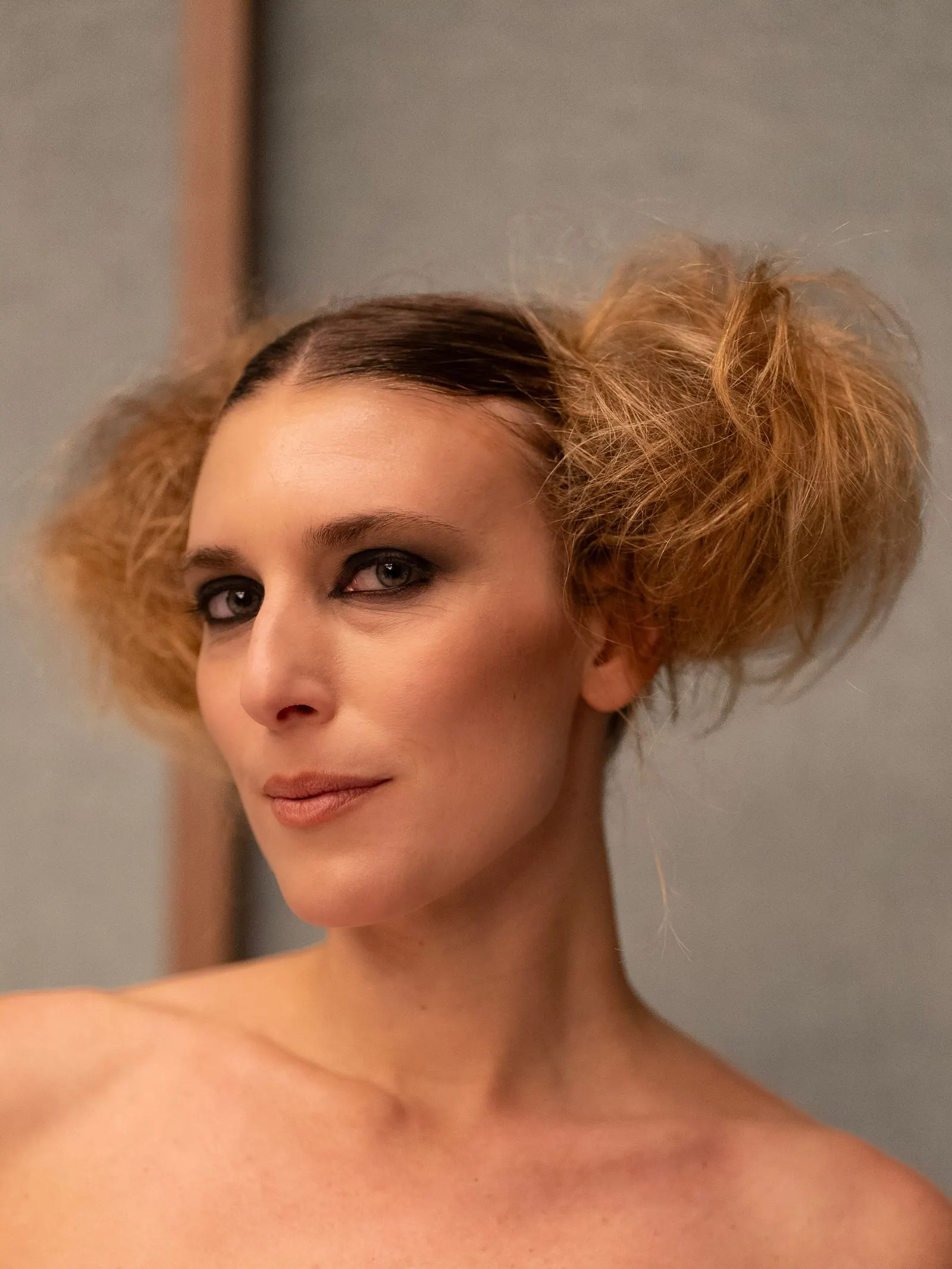 Two structured buns and a slicked centre part — a runway look we soften for everyday wear.