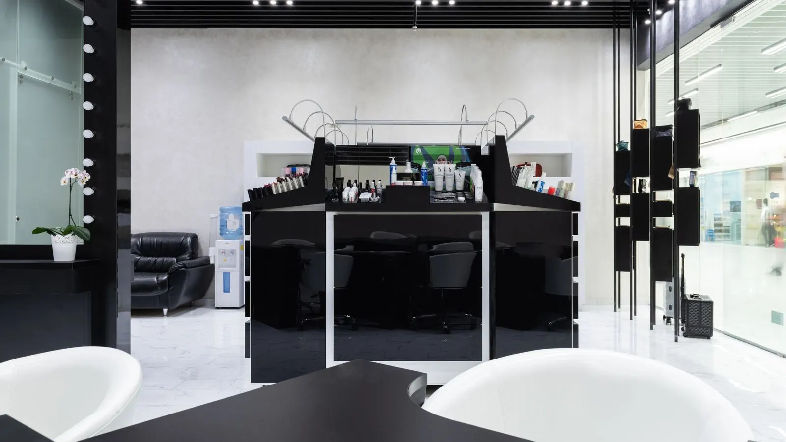 A sleek black and white salon interior with styling stations and a reception counter